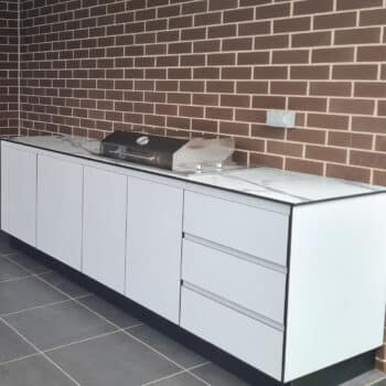 White Outdoor Kitchen With Stainless Steel Hood Cooktop and Calcutta Grey Benchtop